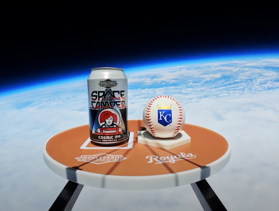 A can of Space Camper Cosmic IPA and a Kansas City Royals baseball sit on a small round table with "Boulevard" and "Royals" logos, floating high above Earth with the curvature and atmosphere visible in the background.